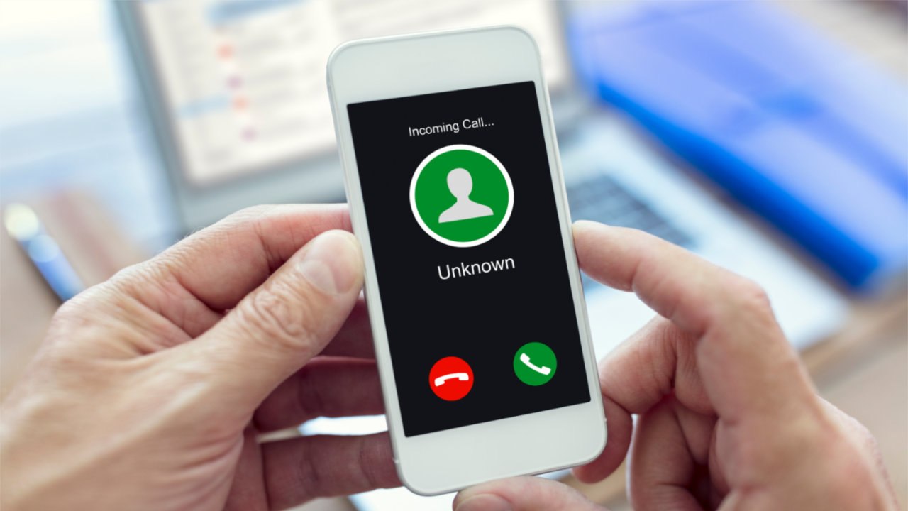 Person holding mobile phone displaying Unknown Caller