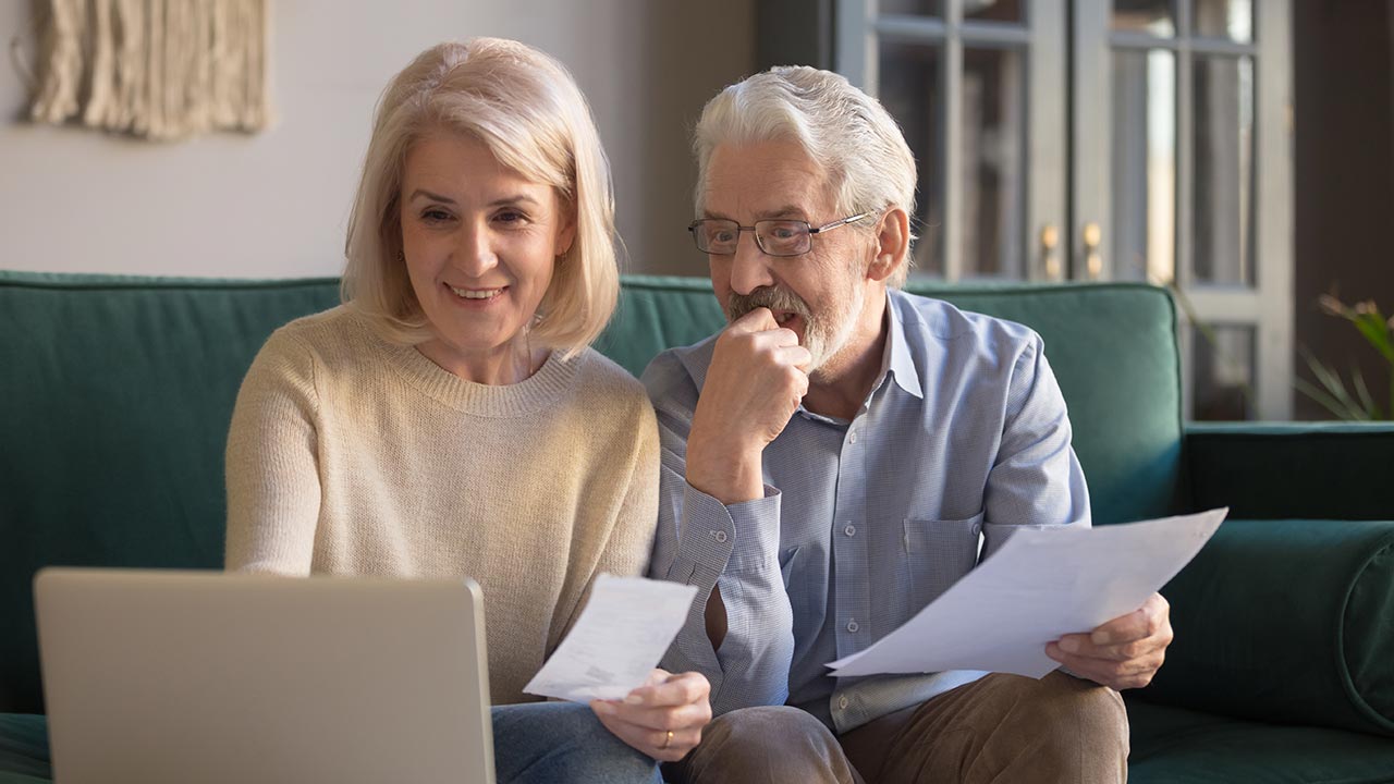 Older couple sitting on couch with laptop