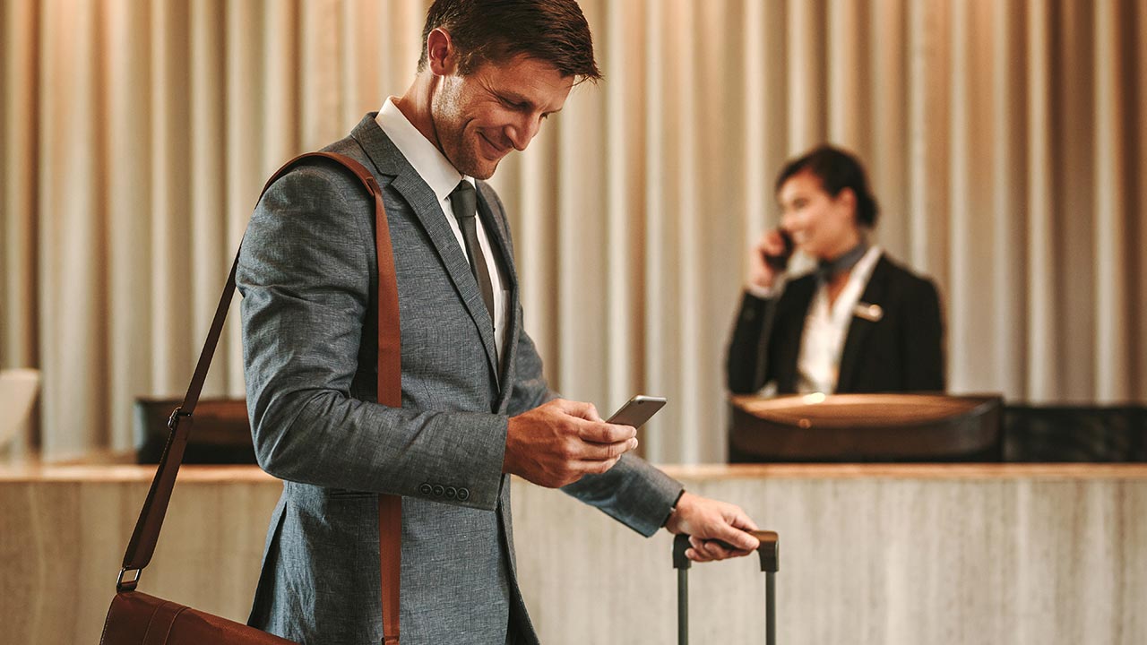 Man walking through hotel lobby looking at mobile phone.