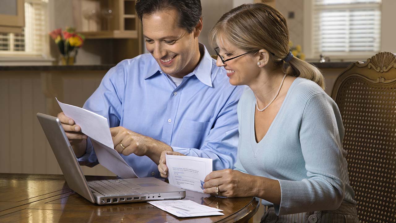 Husband and wife reviewing bills at laptop