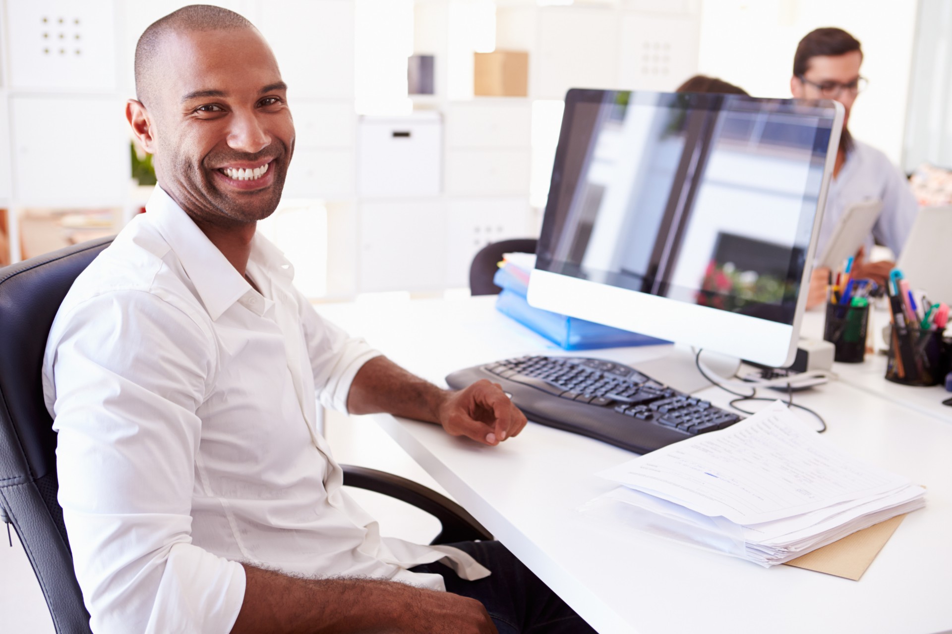 Man smiling sitting a desk.